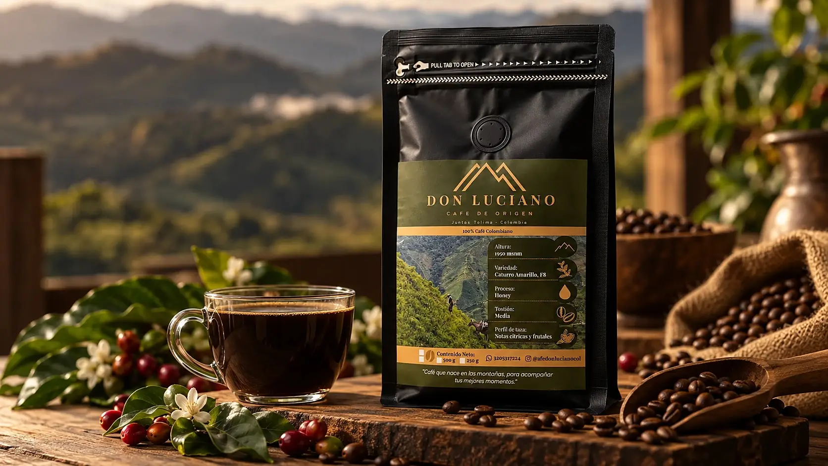 Bolsa de Café Don Luciano Honey sobre una mesa de madera frente a las montañas, con una taza de café, cerezas y flores de café, y granos tostados en un costal.